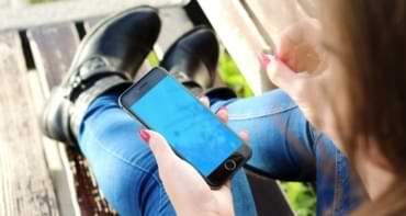 sittande tjej i jeans och boots med mobil - native app Betsson